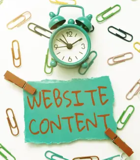 A green alarm clock and scattered paper clips surround a note that reads "WEBSITE CONTENT" in orange ink